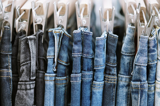 A close up of a blue denim row of jeans hanging on a rack. of different colors and styles. Concept of variety and choice.	