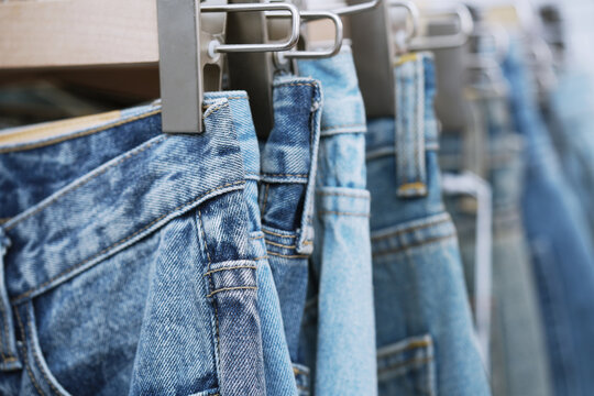 A close up of a blue denim row of jeans hanging on a rack. of different colors and styles. Concept of variety and choice.	