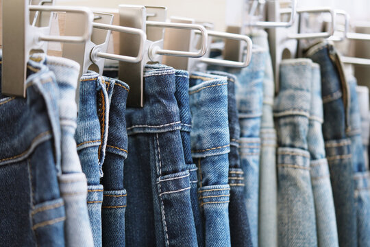 A close up of a blue denim row of jeans hanging on a rack. of different colors and styles. Concept of variety and choice.	