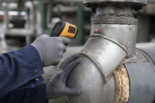 Gloved Industrial Technician Hands Aiming Infrared Laser Thermometer at Pipe Elbow Joint Laser Dot Visible on Metal Surface Damaged Insulation Predictive Maintenance Inspection
