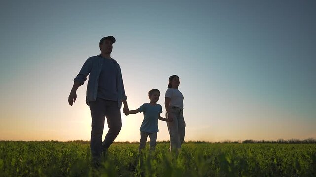 Father walking daughter son field. Family silhouette holding hands under sunset. Together walking field sunset smiling. Daughter son trust father walking field. Family close holding hands at sunset.