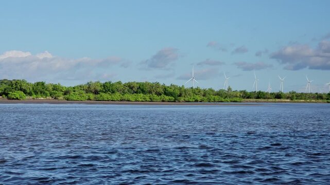 Green energy landscape: Giant wind turbines rising behind lush tropical forests on the banks of Munda&uacute; river.
