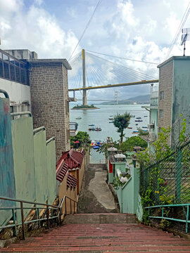 View of a suspension bridge and harbor from a village staircase