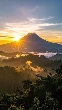 Majestic mountain peak illuminated by the golden rays of sunrise over a lush forest canopy.