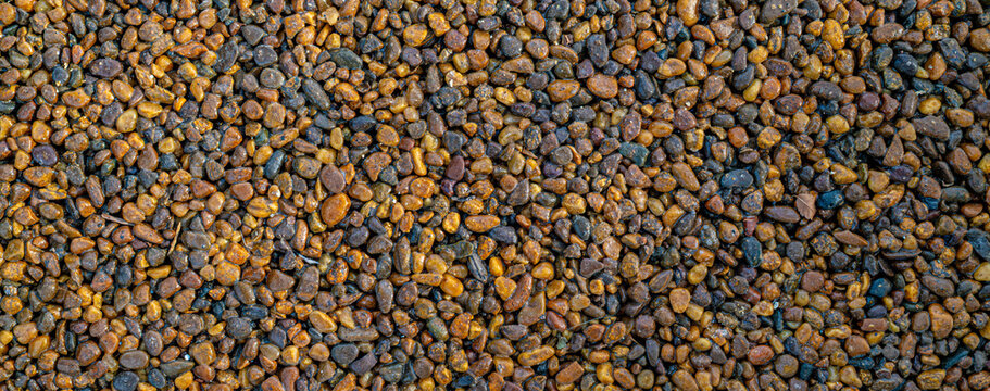 Close up texture of small brown golden gravel pebbles scattered on ground, natural landscaping and construction material concept