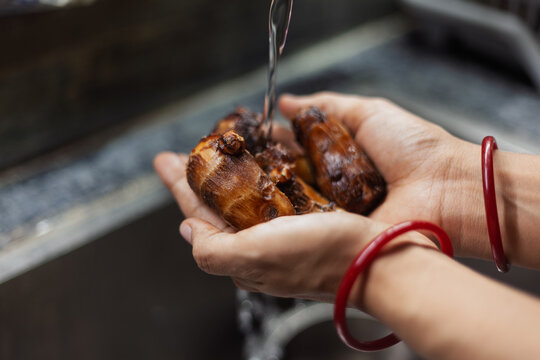 Indian female hands washing boiled taro roots in kitchen sink