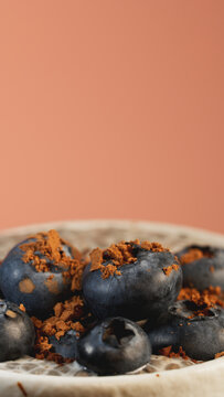 Macro shot of chia pudding with blueberries and cocoa powder in a cup on terracotta background. Healthy dessert for cafe menu, social media stories template, mobile wallpaper and wellness advertising.