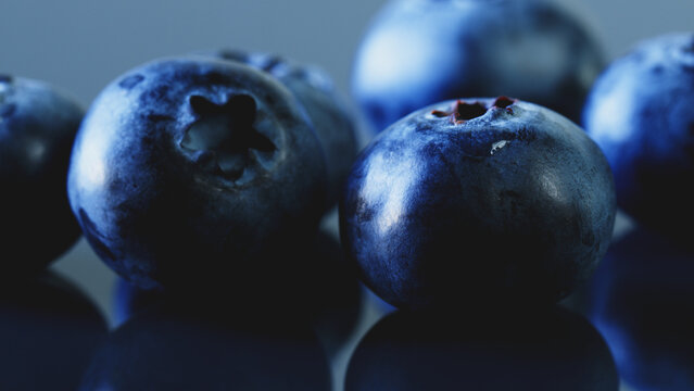Macro shot of fresh blueberries with reflection on glass surface. Juicy berries on pastel blue background for healthy food blog, recipe cover, web banner, advertising, and social media template.