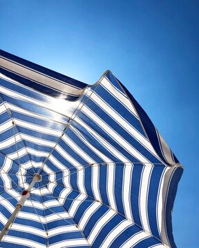 A blue and white beach umbrella opened towards the sky. Vacation and sunshine. Antalya, Turkiye.