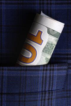 Rolled ten dollar bill tucked into a blue plaid shirt pocket, symbolizing savings, finance, or personal budget.