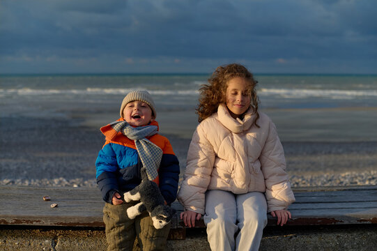 Brother and sister sitting by the sea