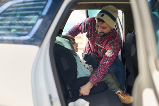 A dad buckles his son into a car seat