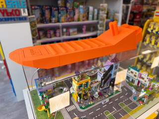 Fototapeta premium Orange toy airplane displayed on top of a lego city model in a toy store