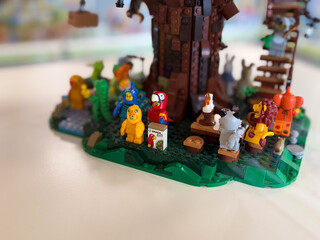 Obraz premium Lego minifigures gathered around a tree in a forest scene with small props and colorful characters on a tabletop display.