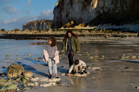 mother with two children walking on the seabed after low tide