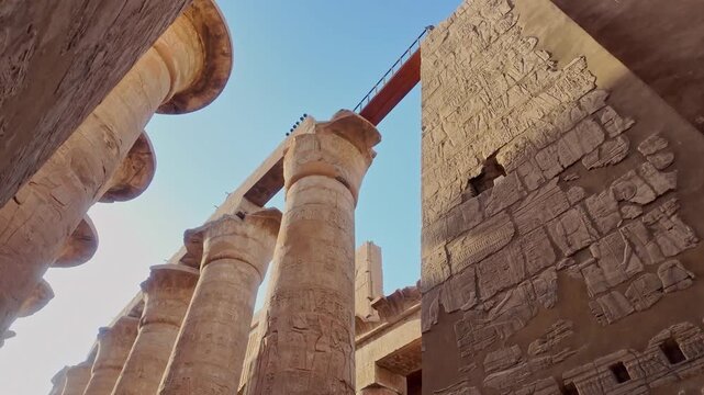 Ancient stone columns and walls of the karnak temple complex in luxor, egypt, featuring intricate hieroglyphic carvings and reliefs