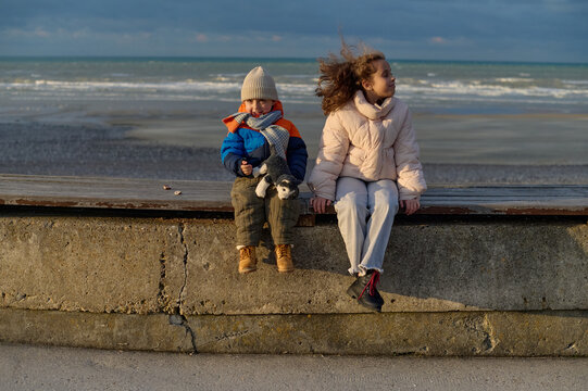 Brother and sister sitting by the sea