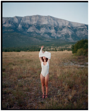 Woman pulling a shirt over her head standing in the desert 