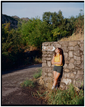 Woman leans against an old stone wall of a camping 