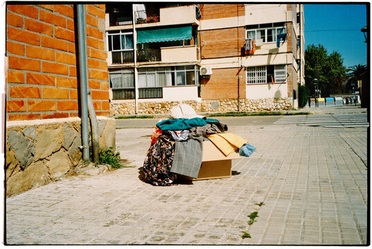 a box overflowing with clothes beside apartment buildings, 35mm film