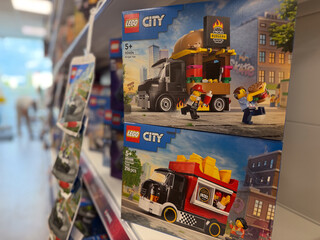 Obraz premium Boxed lego city toy sets displayed on a store shelf in a retail aisle, with colorful food truck models and shallow depth of field.