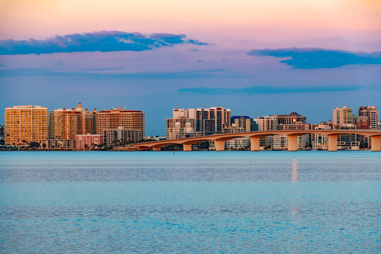 Beautiful panoramic view of the downtown Sarasota skyline in Florida at sunset, showcasing high rise buildings and the John Ringling Causeway bridge over the bay.