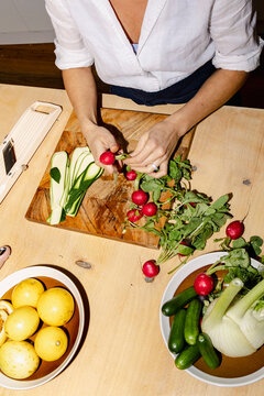Hands trimming radishes for catered dinner in home kitchen