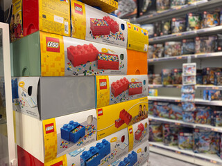 Obraz premium Stack of lego toy boxes in a store aisle with shelves of games and toys in the background