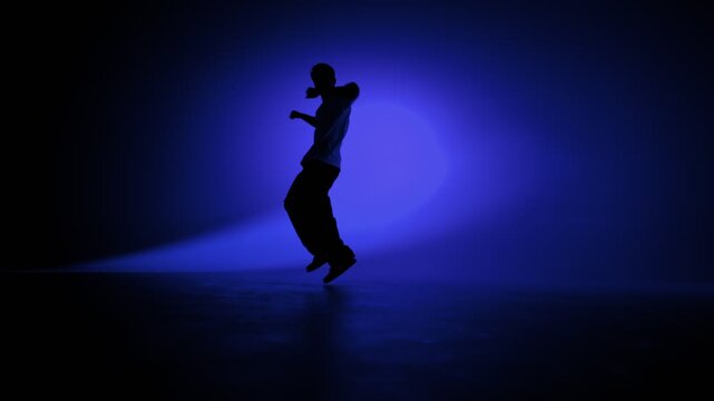 Hip hop dancer striking a strong solo pose under blue light