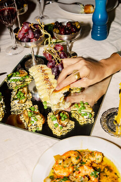 Hand taking appetizer from shared dinner party platter