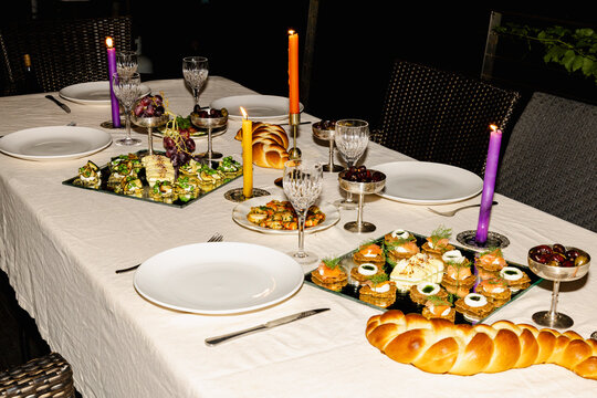 Catered outdoor dinner table with challah bread and candles
