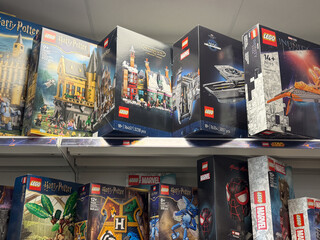 Fototapeta premium Assorted lego toy boxes on store shelves in a retail shop, featuring harry potter, marvel and fantasy themed building sets.