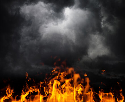 Dramatic flames rising beneath dark storm clouds, creating a powerful scene of destruction, danger, and extreme weather. Fiery blaze contrasts with dense black smoke and ominous sky