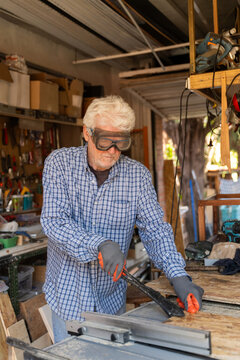 Elderly Man Working in a Garage Filled With Tools and Wood