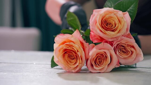 Young florist making bouquet of roses and dried flowers at workplace. Floral artist working in flower shop studio. Floristry showing masterclass on creating flower arrangement. Small woman business.