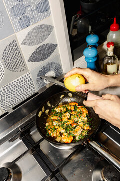 Zesting lemon over prawns while cooking seafood at home