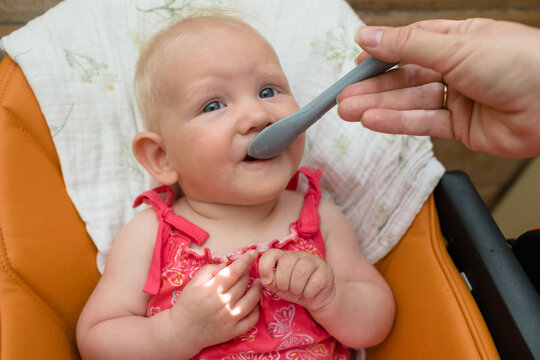 Baby girl eats porridge in the kitchen
