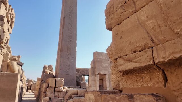 Revealing view of a massive ancient obelisk inscribed with egyptian hieroglyphs among the stone ruins of the karnak temple complex in luxor
