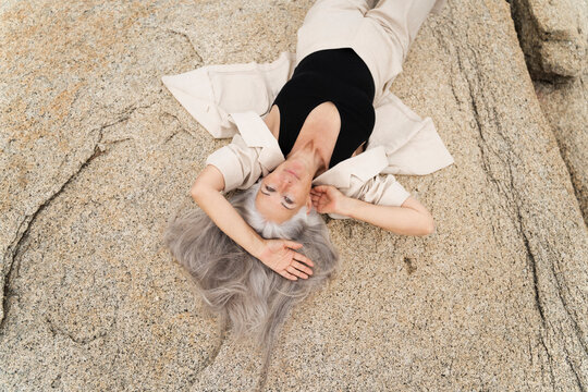 White Haired Woman Lying relax On Rock