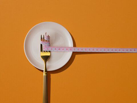 Fork with measuring tape on plate symbolizing diet and weight