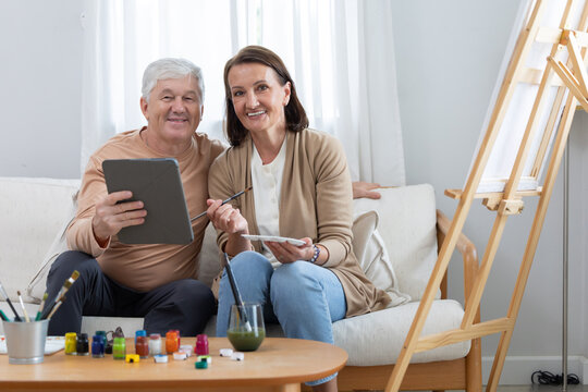 Elderly couple painting together in their home during a sunny afternoon