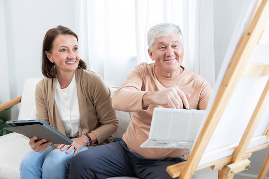 Elderly couple painting together in their home during a sunny afternoon