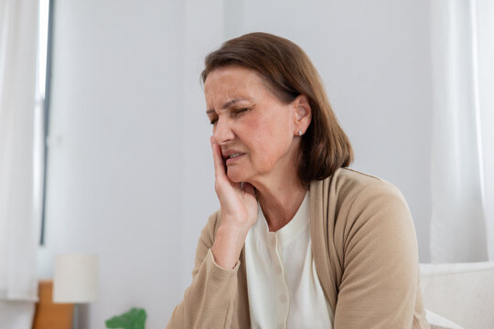 Mature woman touching her cheek suffer from toothache