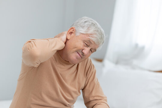 Older man sitting on bed holding his neck in pain  suffer from neck pain during morning