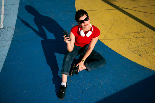 Woman using smartphone and headphones on colorful urban ground
