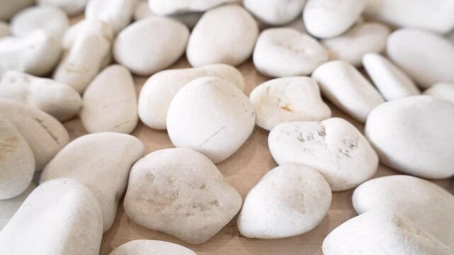 Smooth white pebbles and stones scattered on a light-colored surface, ideal for minimalist backgrounds or garden decor.