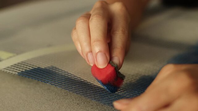 Applying paint with sponge on textile mesh for mixed media artwork