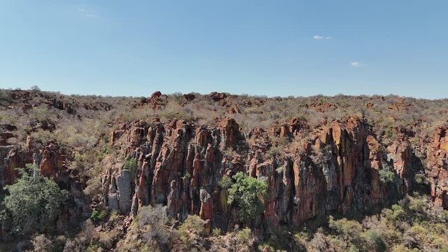 Cinematic aerial footage of majestic red sandstone cliffs and rugged escarpments in the arid wild savanna of Namibia, Africa. Epic geological formations.