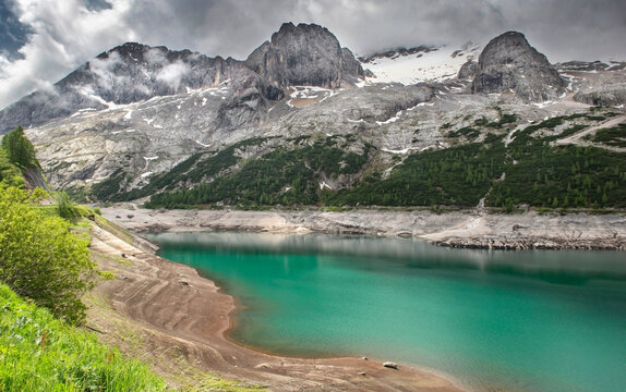 Marmolada glacier and Lake Fedaia dam with beautiful turquoise blue water under a cloudy sky in Dolomite mountains val di Fassa in Italy