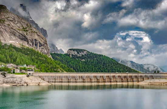 Lake Fedaia dam with beautiful iDolomite mountains under a cloudy sky in Trento, Italy